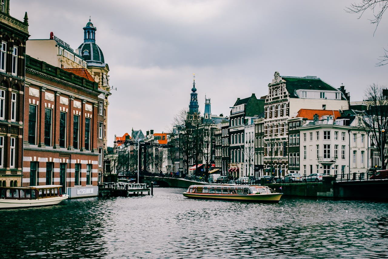Charming canal scene in Amsterdam with historic architecture and a passing boat.